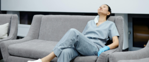 Tired healthcare worker in scrubs resting on a couch during a break